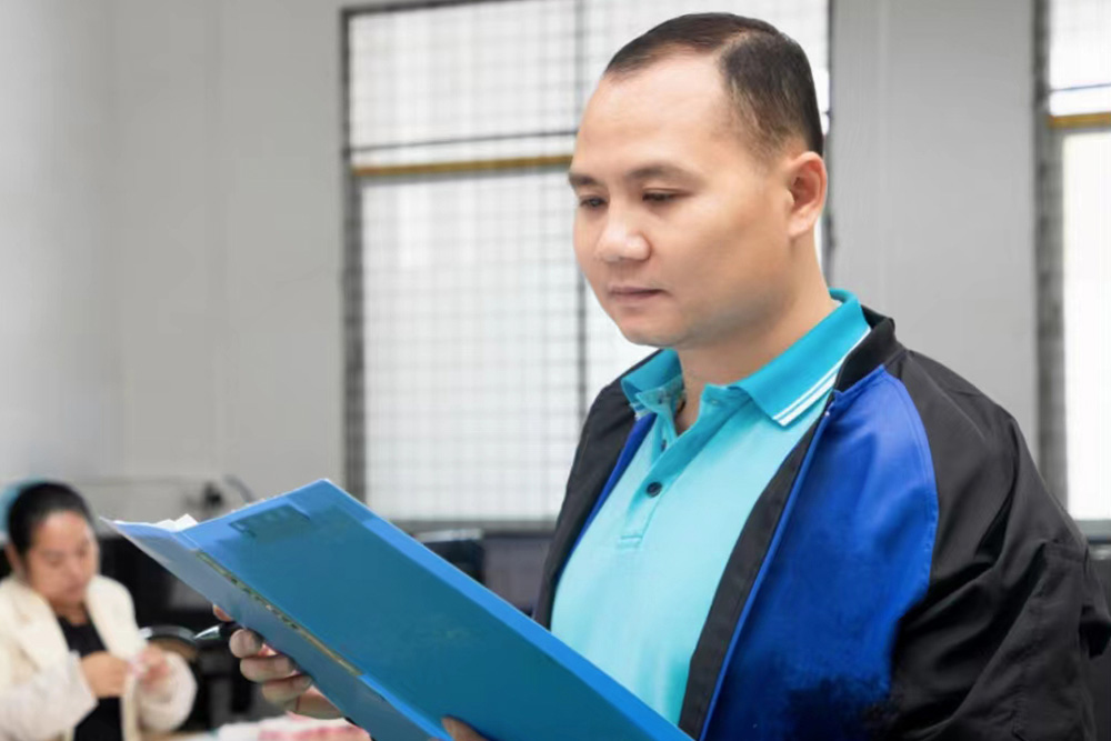 A worker is holding a quality record sheet for inspection and recording on a production line.